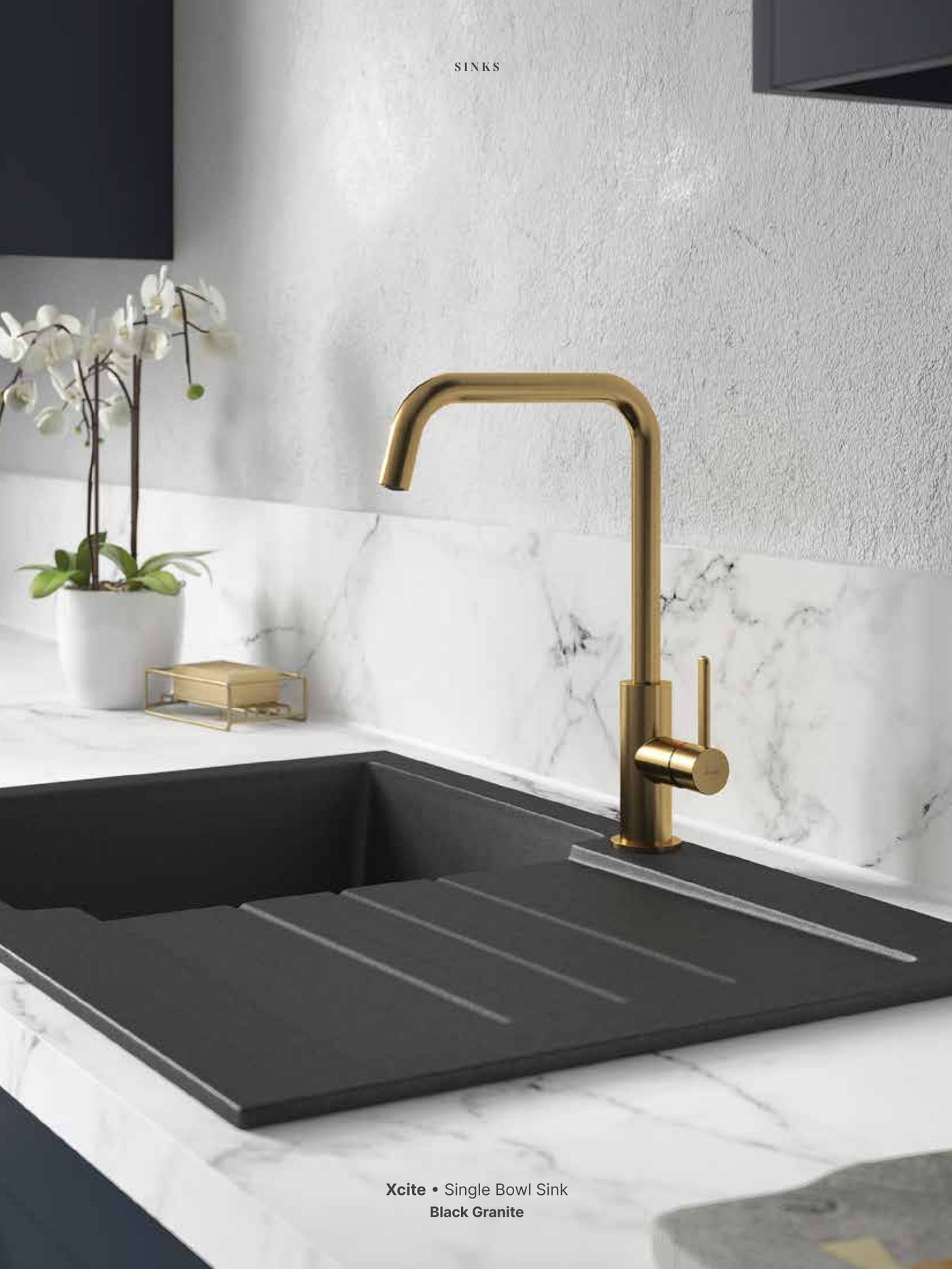 Black composite sink with a brass tap on a marble worktop